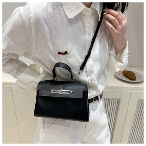 Close-up of a black minimalist kelly-style handbag with silver clasp and thin shoulder strap