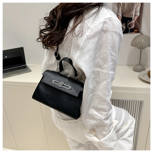 Detail of elegant black leather handbag featuring polished silver metal twist lock closure