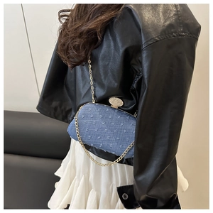 Detail of blue denim crossbody bag with textured dots and rhinestone buckle on model