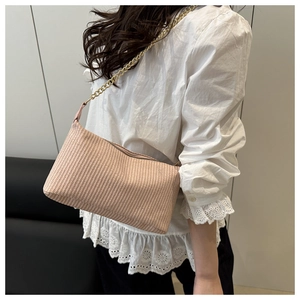 Detail of light pink woven pillow bag with a delicate golden metal chain strap on model