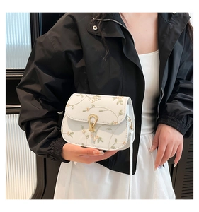 Détail du sac bandoulière blanc avec broderie florale et fermoir tournant en fer à cheval