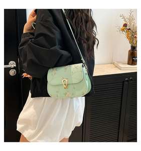 Detail of mint green crossbody bag with gold floral embroidery and U-shaped metal clasp
