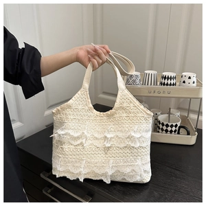 Détail de volants en dentelle blanche et poignée en similicuir sur un grand sac cabas