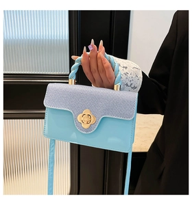 Gros plan du sac à main bleu clair en denim avec fermoir fleur dorée et anse corde