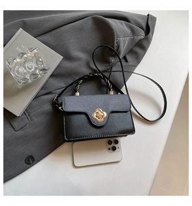 Détail du sac bandoulière noir avec fermoir fleur dorée et poignée tressée chic