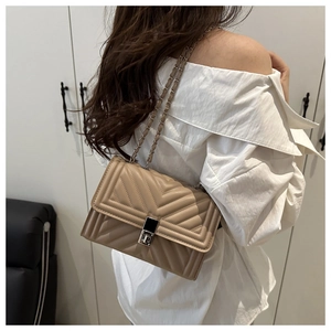 Detail of chevron quilted crossbody bag with metal lock and chain strap on a model