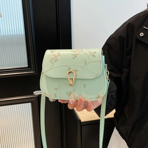 Mint green crossbody bag with floral embroidery and gold U-shaped metal buckle detail