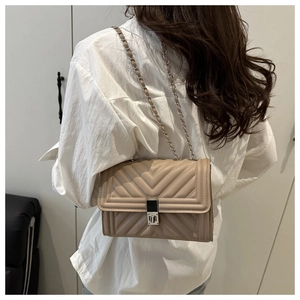 Détail du sac à rabat matelassé beige avec chaîne argentée et fermoir pivotant en métal