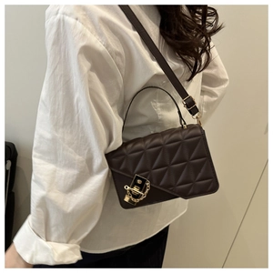 Détail du sac à bandoulière matelassé marron foncé avec fermoir doré et texture