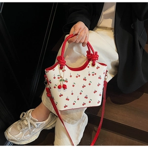 Détail du sac en cuir blanc avec imprimés cerises et breloque cerise 3D