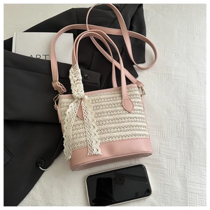 Macro detail of pink leather and woven straw bag with floral lace scarf and gold hardware