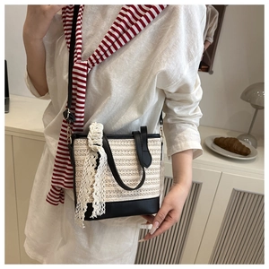 Straw bucket bag detail with white lace bow and black leather trim on striped dress
