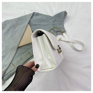 Detail of white quilted crossbody bag showing gold lock and accordion fold compartments