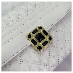Detail view of quilted white leather bag with vintage gold buckle and black stones