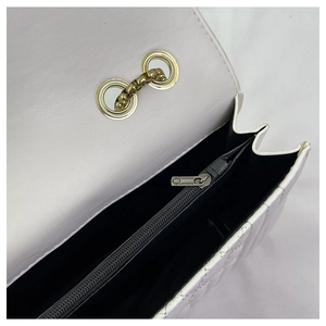 Detail view of white quilted shoulder bag with golden chain and black interior compartments