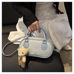 Detail view of light blue lychee pattern bowling bag with cute bear charm and long strap