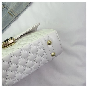Detail of white quilted leather bag showing golden metal studs and textured stitching