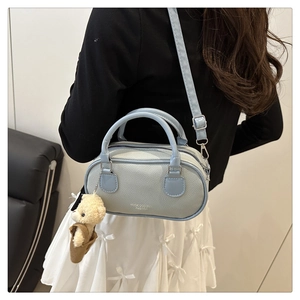 Close-up of light blue leather handbag featuring textured grain and a cute bear charm