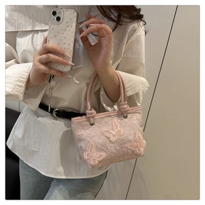 Detail of pink lace bucket bag featuring intricate floral embroidery and butterfly appliques