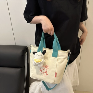 Minimalist canvas tote with blue handles featuring a cartoon bear and plush dog charm