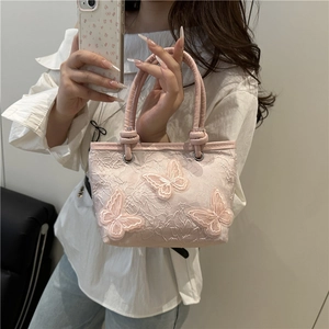 Sac seau en dentelle rose avec broderie papillon 3D porté par un mannequin mode