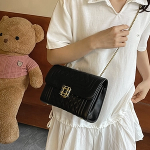 Classic black quilted shoulder bag with gold chain strap worn by model in a cozy setting