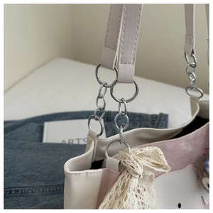Detail des silbernen Kettenhaube mit Spitzenschleife auf rosa-weißer Comic-Tasche