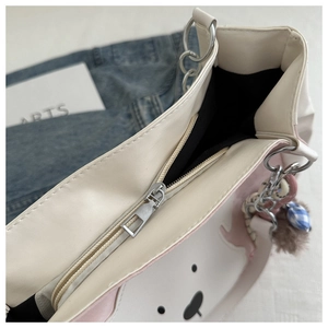 Detail der rosa-weißen Tragetasche mit Metallreißverschluss und Plüsch-Anhänger