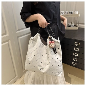 Close-up of quilted floral tote bag featuring thick rope handles and a plush bear charm