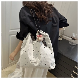 Detailed close-up of corduroy tote bag with star patterns and cute plush bear charm
