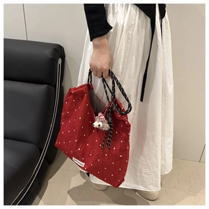 Detail of red floral tote bag featuring a woven rope handle and cute plush bear charm