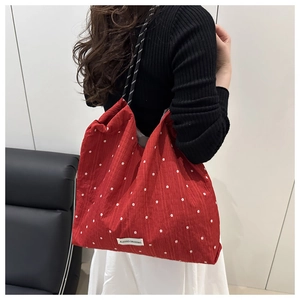 Detail of red floral mesh tote bag with white flower patterns and woven rope straps
