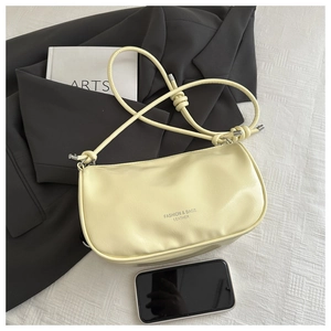 Pale yellow ruched baguette bag shown with a smartphone for scale comparison