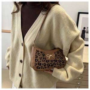 Close-up of leopard print shoulder bag with gold bow clasp and brown leather trim