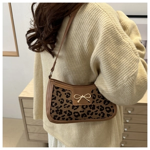 Sac baguette léopard avec nœud doré porté sur l'épaule avec un pull en maille beige