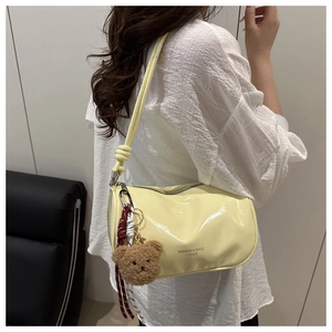 Detail of yellow cylinder bag with knot shoulder strap and plush bear charm decoration
