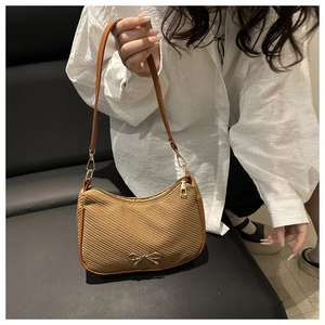 Detail of a brown woven underarm bag featuring a vintage golden bow metal clasp