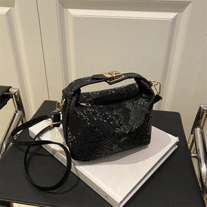 Elegant black snake texture pillow bag with gold hardware on a white decorative stand