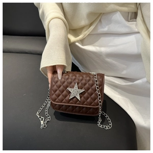 Close-up of brown quilted crossbody bag with silver glitter star and chain strap