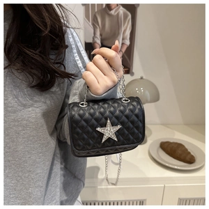 Detail of black quilted crossbody bag featuring a large rhinestone star and silver chain