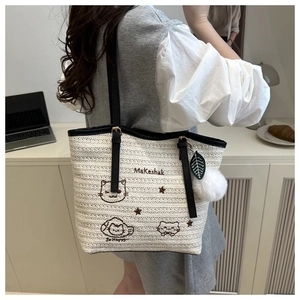 Détail du sac cabas tissé avec broderie chat, étoiles et breloque pompon moelleuse