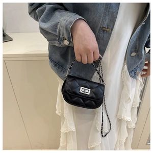 Detail of a mini black quilted crossbody bag with silver chain strap and metal turn-lock