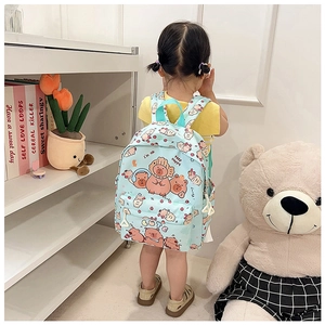 Light blue backpack with cute capybara print and slogan worn by a child in a cozy room