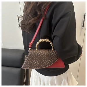 Detail of vintage patterned crossbody bag with gold twisted metal handle and red trim