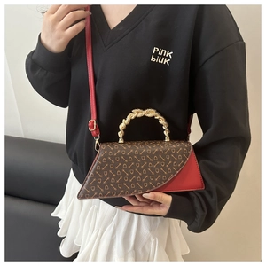 Detail of artistic gold twisted handle and red leather contrast on fashion crossbody bag
