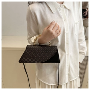 Detail of a vintage-style brown patterned crossbody bag with a gold twisted metal handle