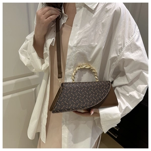 Detailed shot of brown monogram handbag featuring unique gold twisted metal handle