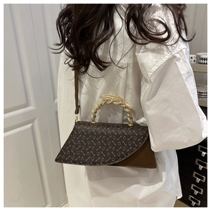 Detail of vintage patterned crossbody bag with a distinctive gold twisted metal handle
