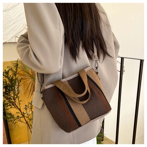 Detailed close-up of striped canvas tote bag texture with adjustable leather shoulder strap