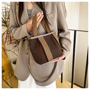 Detail of striped mini bucket bag featuring woven textures and brown shoulder strap